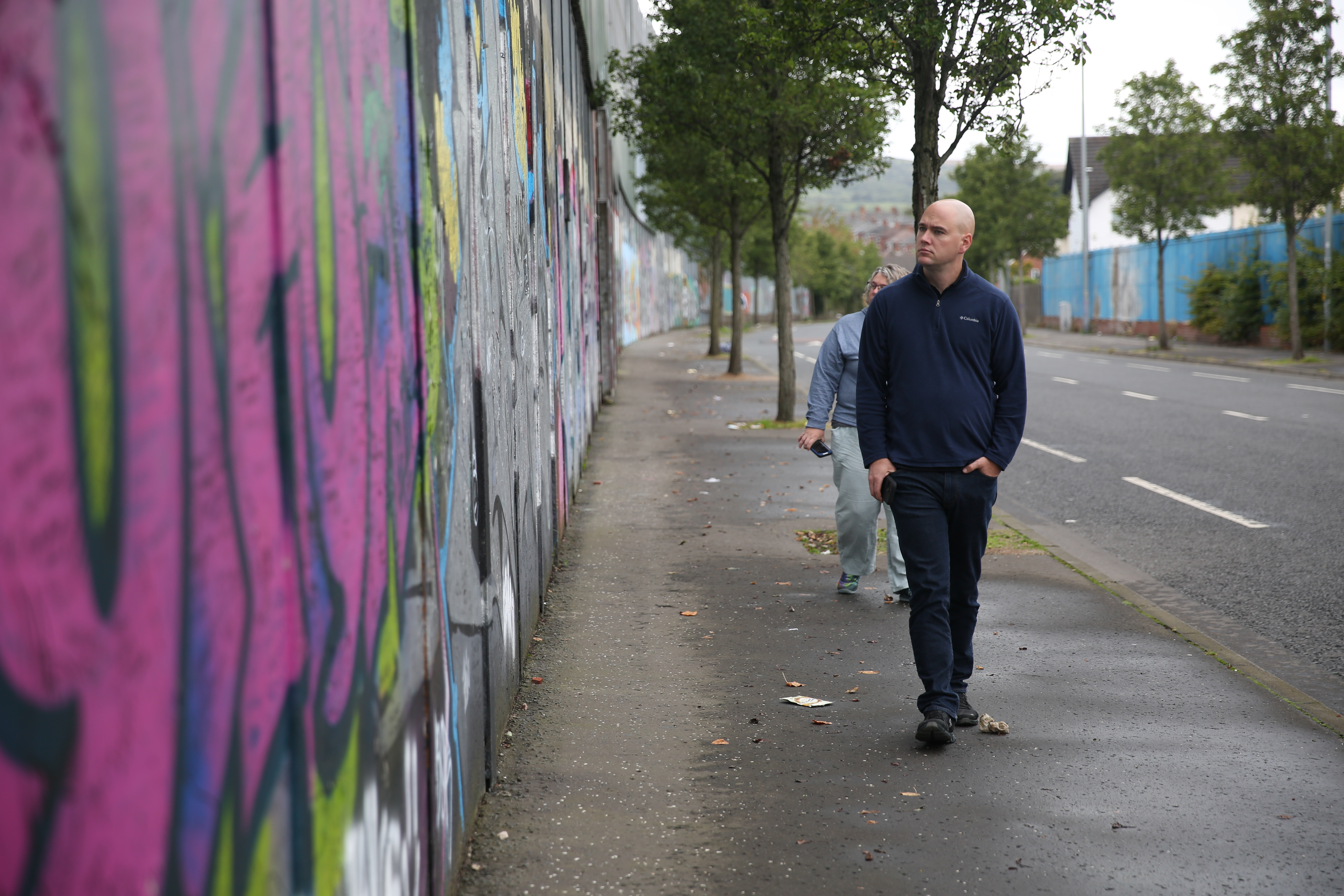 WPLP cohort seven members Thomas Horrocks and Melody Merida walk along the Peace Wall on Cupar Way in Belfast. 