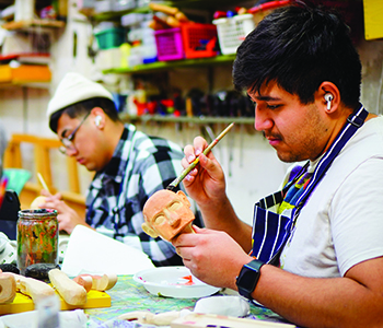 Jonathan Gonzalez ’24 (center) and Dario Benuelos ’23 in the beginning stages of painting their puppets